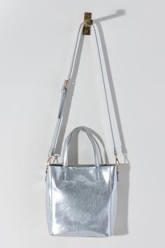 Make a statement this summer with Shiraleah's Maddie Mini Tote. Made from metallic PU, this shiny accessory is sure to turn heads. Add some versatility to your style by wearing with the detachable adjustable cross-body strap or carry with the standard double handles. Pair with other Shiraleah items to complete your look! Features double handles, a detachable adjustable cross-body strap, magnetic snap closure, and 1 inner slip pocket Shiraleah is a trend-driven lifestyle brand focused on the litt Metallic Satchel Shoulder Bag For Everyday Use, Trendy Metallic Bags For Daily Use, Metallic Bags With Silver-tone Hardware For Everyday, Metallic Double Handle Bag For Shopping, Trendy Metallic Travel Bag, Metallic Double Handle Everyday Bag, Metallic Rectangular Shoulder Bag For Everyday, Chic Metallic Bags For Everyday Use, Trendy Metallic Shoulder Bag For Shopping