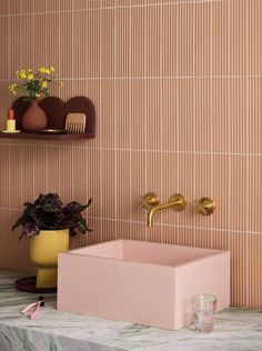 a pink sink sitting on top of a counter next to a potted plant