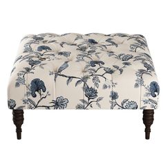 a blue and white floral ottoman with wooden legs on an isolated white background for use as a footstool