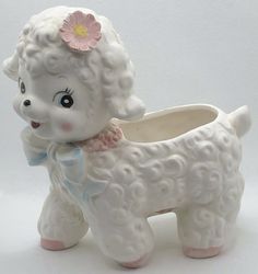 a white ceramic poodle planter with a pink flower on its head