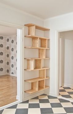 an empty room with black and white checkered flooring on the walls, open shelving unit in the middle