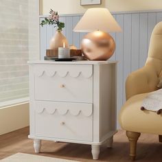 a white dresser sitting next to a chair in a room