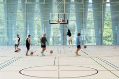 several men playing basketball in an indoor court with many lines painted on the floor and walls