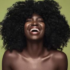 a woman with an afro is smiling and looking at the camera while she has her eyes closed