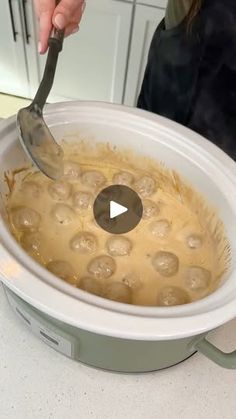 a person stirring food in a slow cooker with a ladle on the side