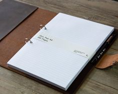 a notepad and pen sitting on top of a brown notebook with writing paper attached to it