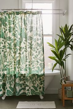 a bathroom with a green shower curtain next to a bathtub and a potted plant