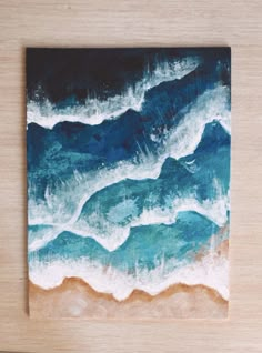 a painting on a wooden surface with waves coming in from the ocean and blue sky