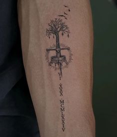 a person with a tattoo on their arm that has a cross and tree in it