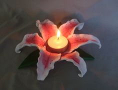 a candle that is sitting in the middle of a flower on a tablecloth with white and red flowers