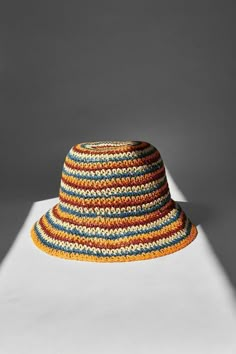 a multicolored hat is shown on a white surface with the shadow from it