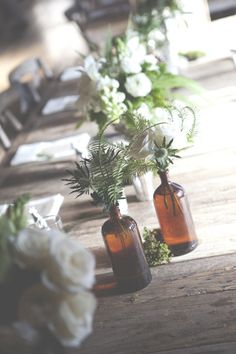 three vases filled with flowers sitting on top of a wooden table next to each other