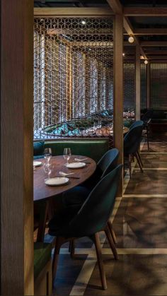 the dining room at an upscale restaurant with wooden tables and green chairs, along with wine bottles on the wall