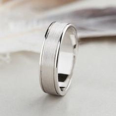 a white gold wedding ring on top of a table