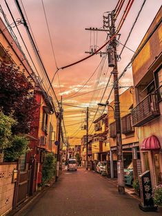 an empty street with power lines above it and cars parked on the sidelines below