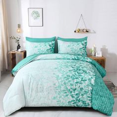 a bed with green and white comforters in a room next to a window,