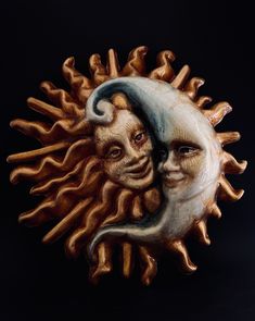 a ceramic sun and moon face on a black background with the image of two people's faces