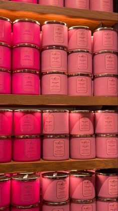 pink candles are lined up on shelves in a store