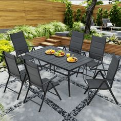 an outdoor dining table with six chairs and plates of food