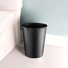 a black trash can sitting next to a white toilet