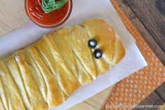 a pastry with blueberries on it sitting next to a bowl of sauce and a napkin