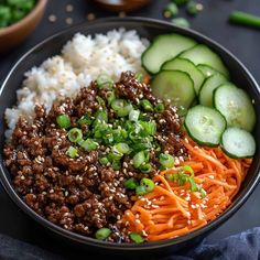 a bowl filled with rice, meat and veggies next to cucumbers