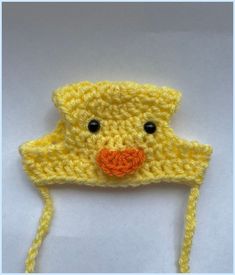 a crocheted yellow ducky hat with black eyes and orange nose is shown