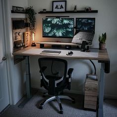 a computer desk with two monitors and a keyboard on it in front of a door