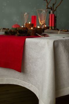 the table is set with red candles and dishes on it, along with other decorations