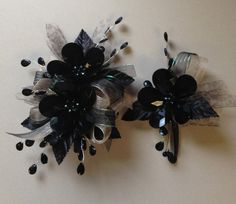 two black and white flowers are sitting on the wall next to each other with ribbons