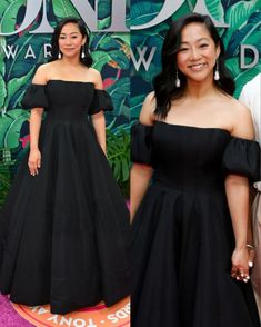 two women in black dresses standing next to each other on a pink carpet with green leaves