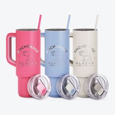 four different colored travel mugs with lids and straw in front of each other on a white background