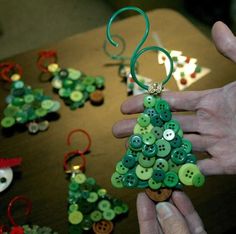 a person holding a green christmas tree ornament with buttons on it's side