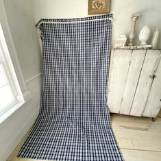 a blue and white checkered blanket sitting on top of a wooden floor next to a window