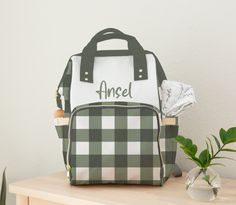 a green and white backpack sitting on top of a wooden table next to a potted plant