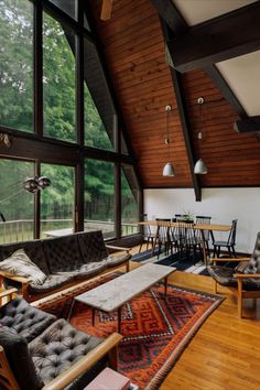 a living room filled with lots of furniture and large windows overlooking the trees in the distance