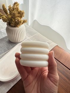 a person holding some kind of white object in their hand next to a potted plant