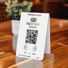 a business card sitting on top of a wooden table next to a potted plant