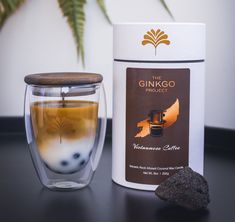 a cup of coffee next to a canister with liquid in it and a rock on the table