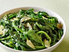 a white bowl filled with green vegetables on top of a table