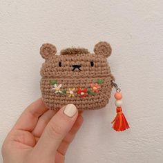 a hand holding a small crocheted bear purse with tassels on it