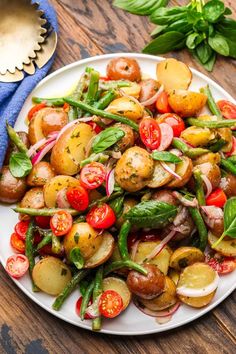 a white plate topped with potatoes and veggies on top of a wooden table