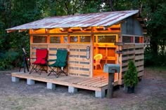 a small wooden shed with two lawn chairs on the front and one chair in the back