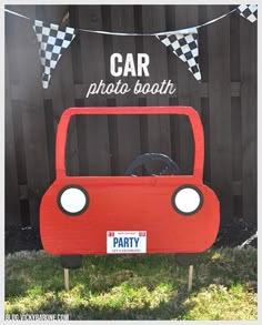 a car photo booth is set up in front of a fence with flags and bunting