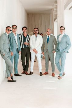 a group of men standing next to each other wearing suits and sunglasses on their heads