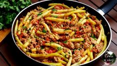 a pan filled with pasta and meat on top of a wooden table