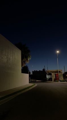 an empty street at night with the lights on and palm trees in the foreground