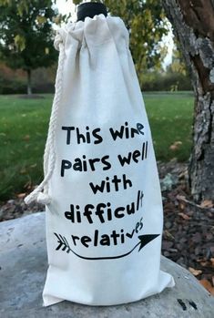 a white bag with black writing on it sitting on top of a rock next to a tree