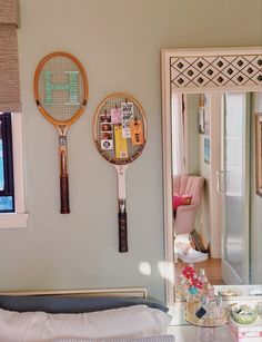 two tennis racquets are hanging on the wall next to a bed in a bedroom