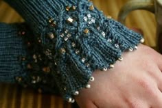 a close up of a person's hand wearing a knitted arm warmer and holding a coffee cup